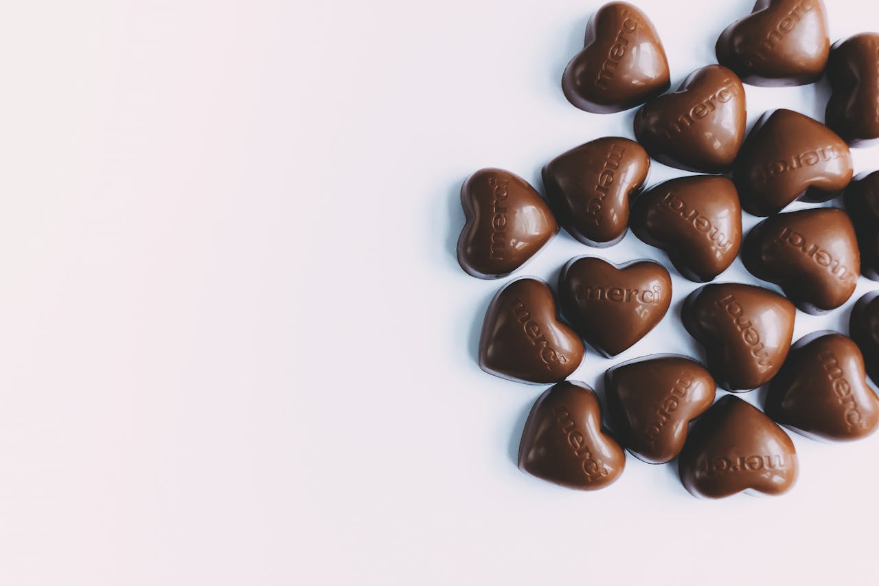 Flat lay of heart-shaped milk chocolates with 'merci' text, perfect for gifting.